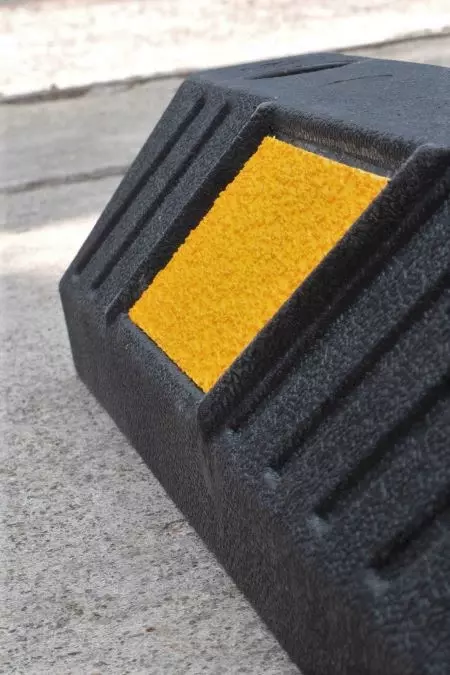 A detailed image of a wheel stop with a yellow reflective film can be observed