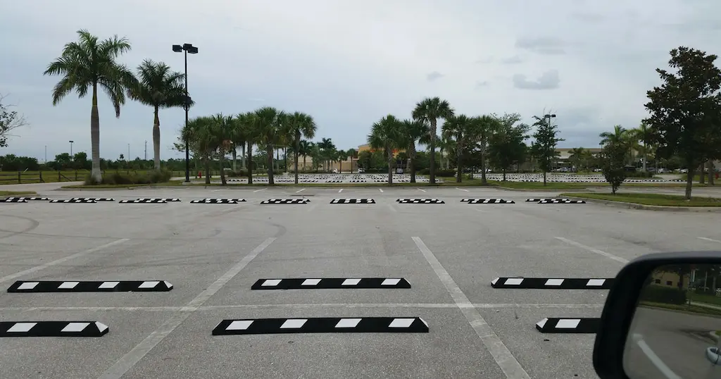 Black parking kerbs with white reflective films installed in a parking lot.