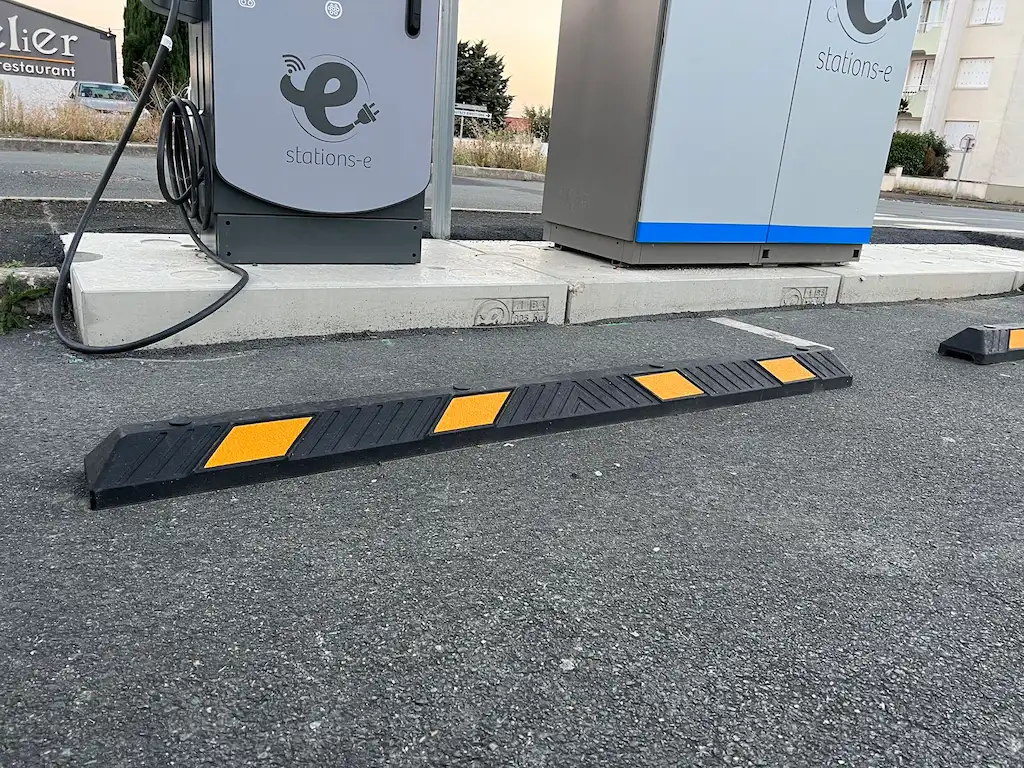 Black and yellow wheel stops are installed in front of the EV charging station to help parking and protect the charging station.