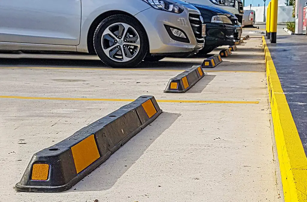 Black parking bumpers with yellow reflective films installed in a parking lot to organize parking.