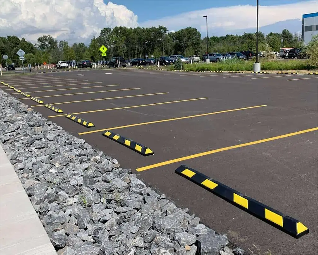 Black and yellow parking curb stops installed at a parking lot.