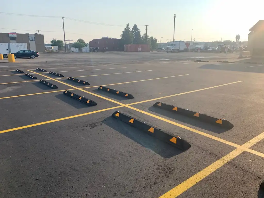 Black and yellow parking curbs installed in a parking lot.