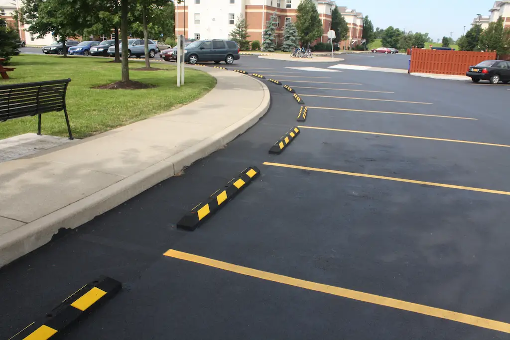 Black parking lot bumpers with yellow markings used to help parking.