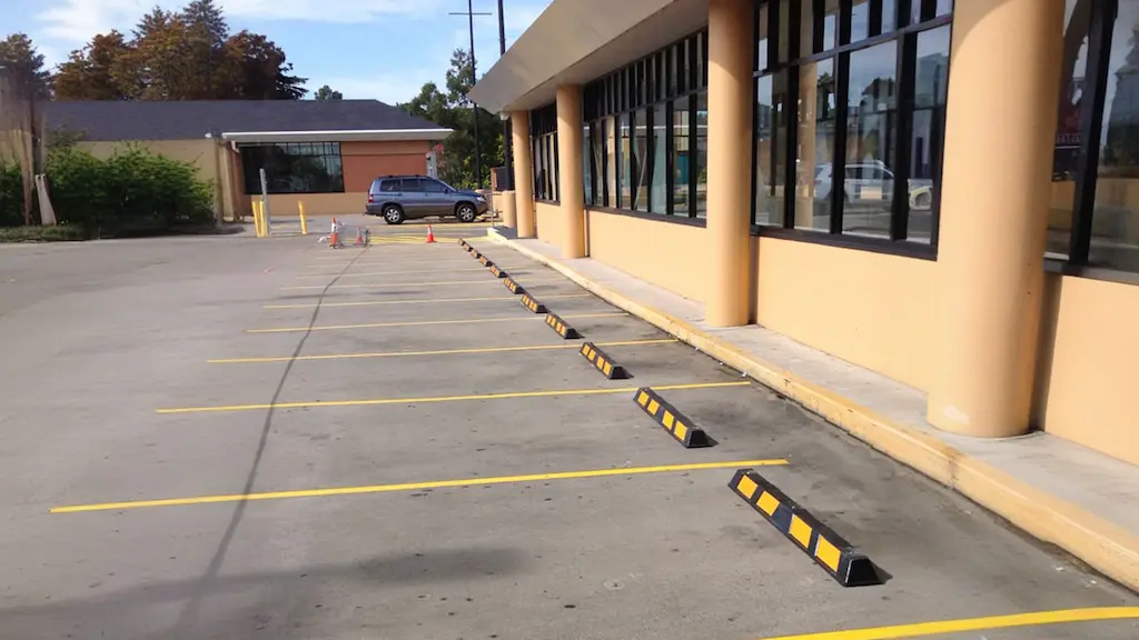 Black and yellow parking lot curb stops used to help people parking.