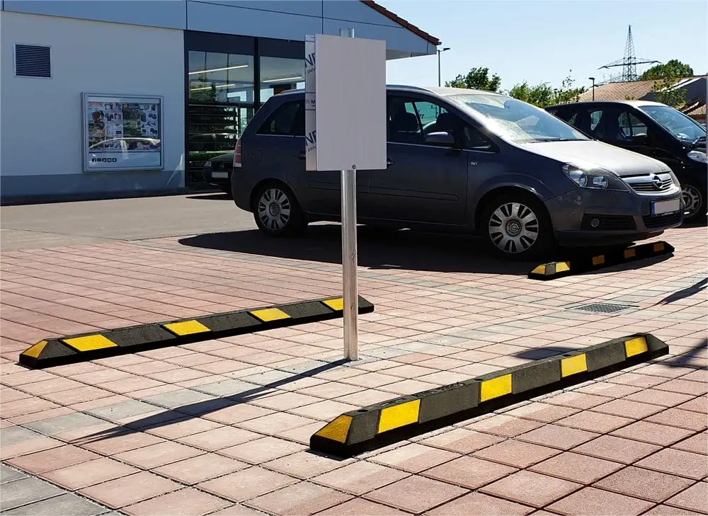 Black and yellow parking lot curbs used to help drivers parking their vehicles safely and accurately.