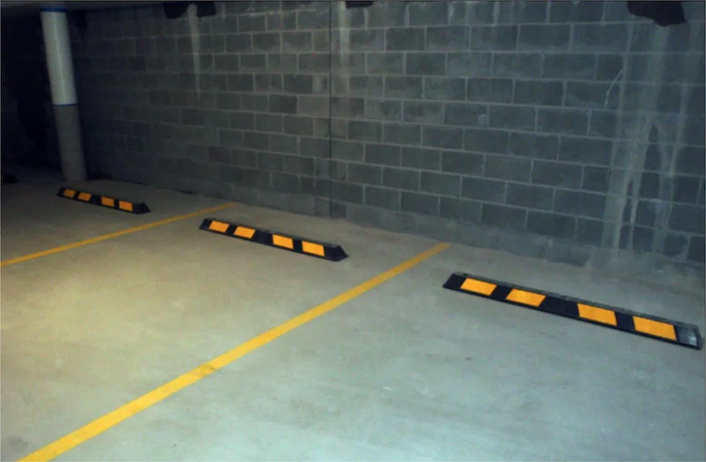 Black parking lot stops with yellow reflective films used to help parking.