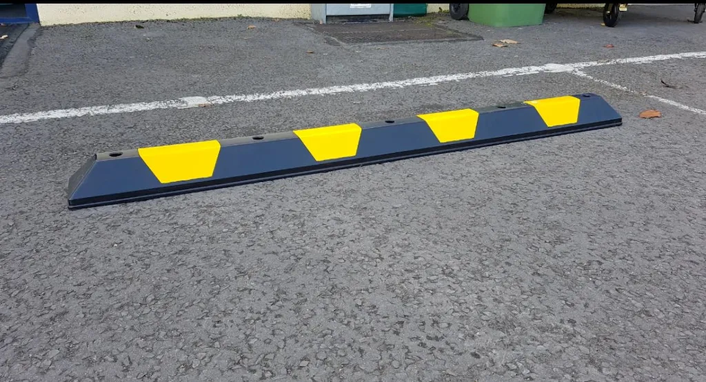 A black and yellow parking block made of recycled plastic.