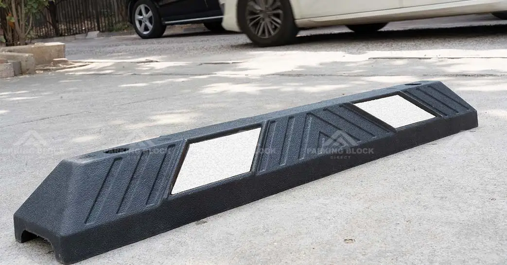 A black plastic-rubber composite car stop with white reflective films manufactured by Parking Block Direct.