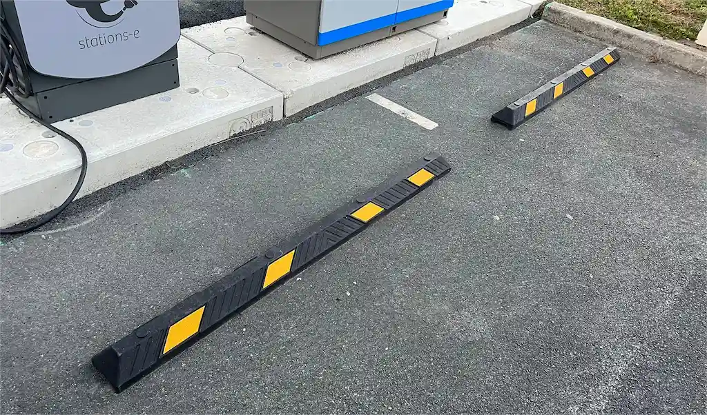 Two Plastic-Rubber composite car stops installed in front of the EV charger station.