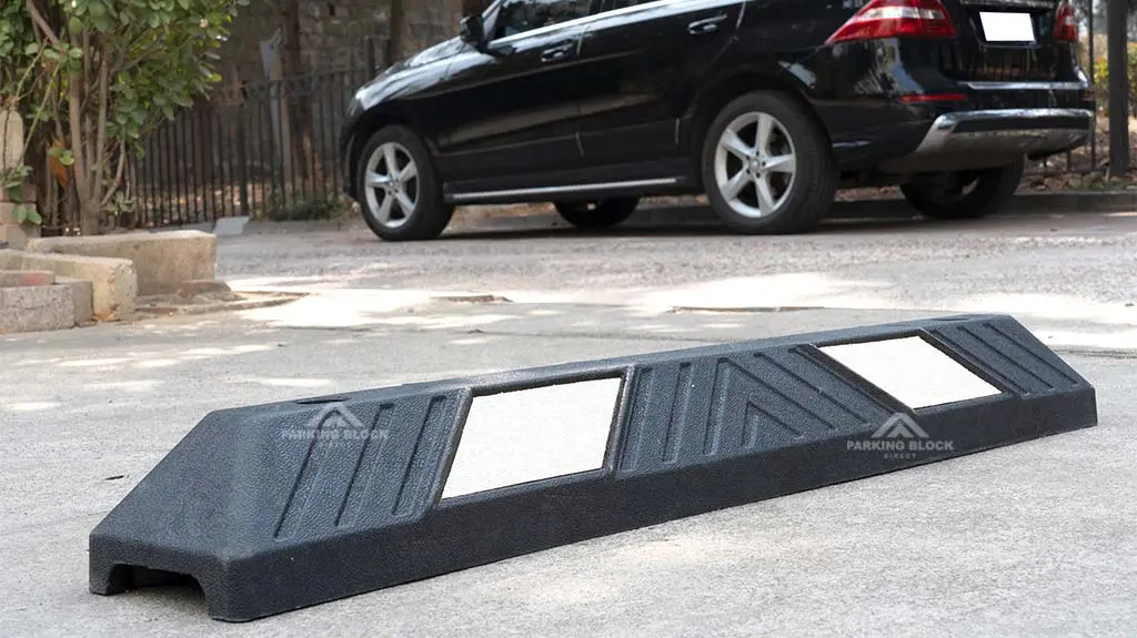 A black plastic-rubber composite parking block with white reflective films manufactured by Parking Block Direct.