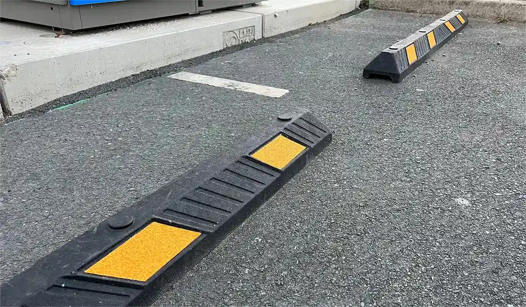 Black parking bumpers made of Plastic-Rubber composite material with yellow reflective films.