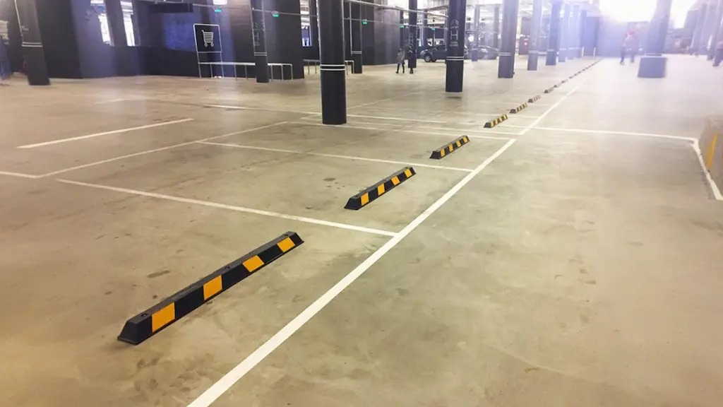 Black wheel stops with yellow reflective films in an underground parking lot.